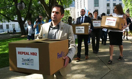 ADDS STATE REP. TITLE - State Rep. Chris Sgro, D-Guilford, who is also executive director of Equality NC, leads a group carrying petitions calling for the repeal of House Bill 2 to Gov. Pat McCrory’s office at the state Capitol building Monday, April 25, 2016, in Raleigh, N.C. Tempers are flaring as supporters and opponents of the new North Carolina transgender law hold competing rallies to sway legislators starting their annual session. (Chuck Liddy/The News & Observer via AP) MANDATORY CREDIT